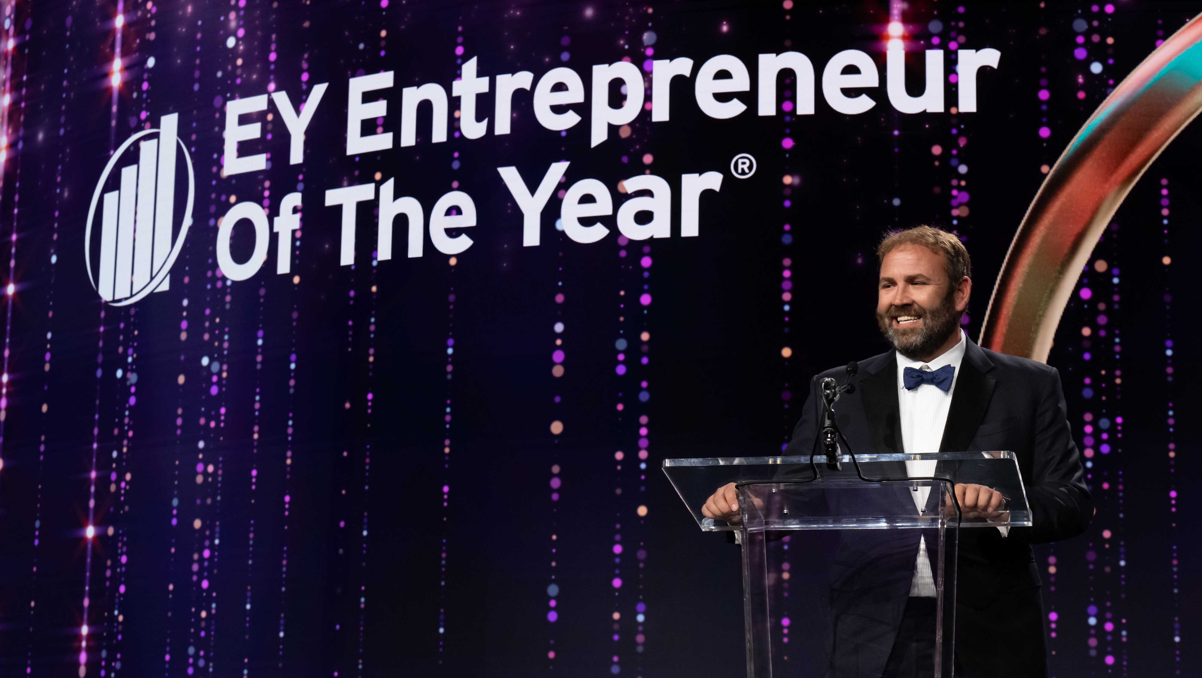 Chris Barnett in a tuxedo at a podium