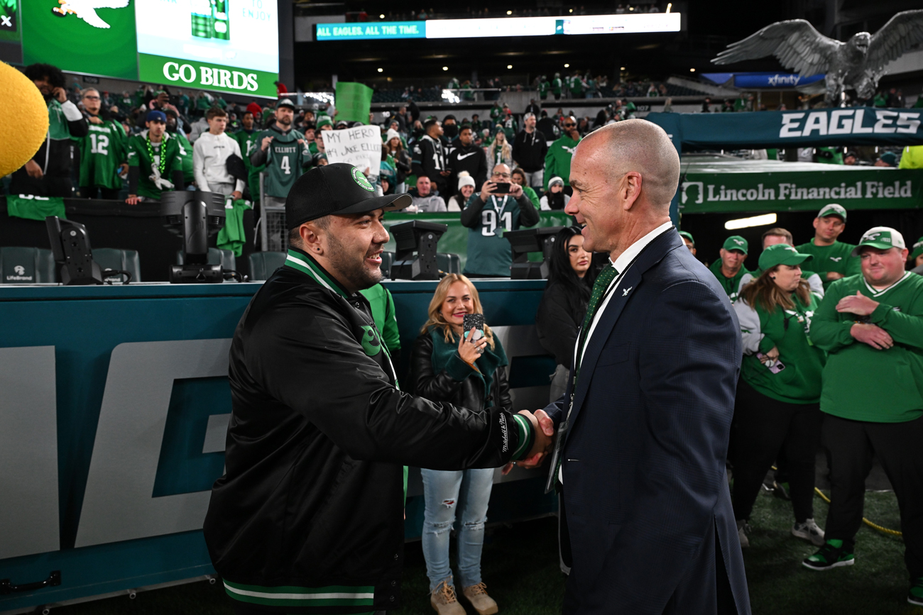 Image of Temple alum greeting Philadelphia Eagles president inside a stadium.