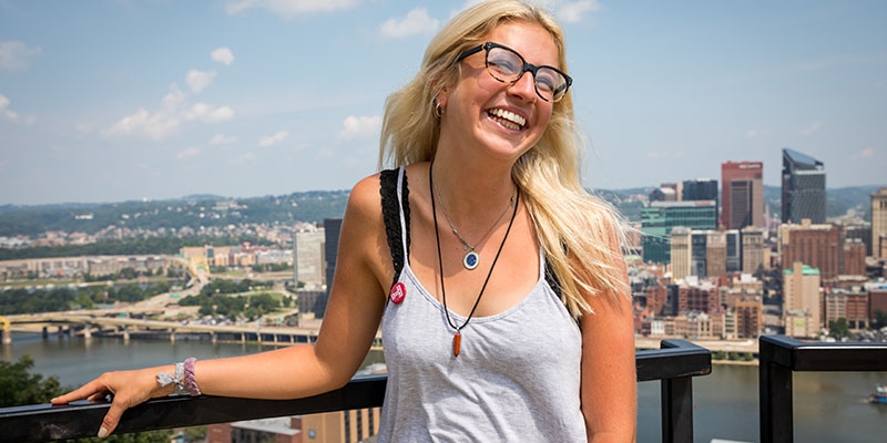Freshman Emma Dowker smiling with the Pittsburgh skyline behind her.