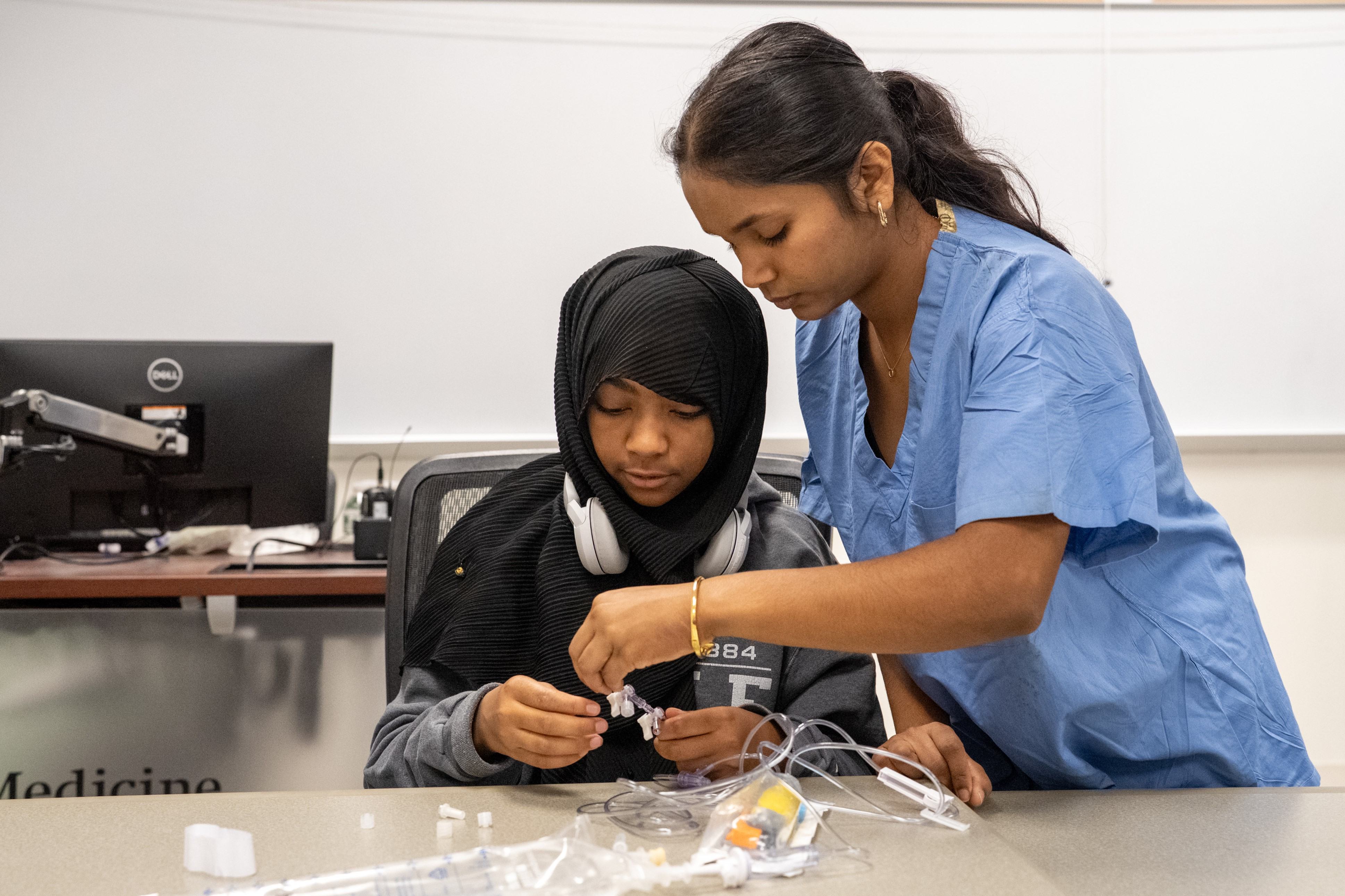 A medical student helps a middle school student perform an activity