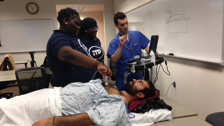 Two medical students showing middle school students a procedure in the hospital.