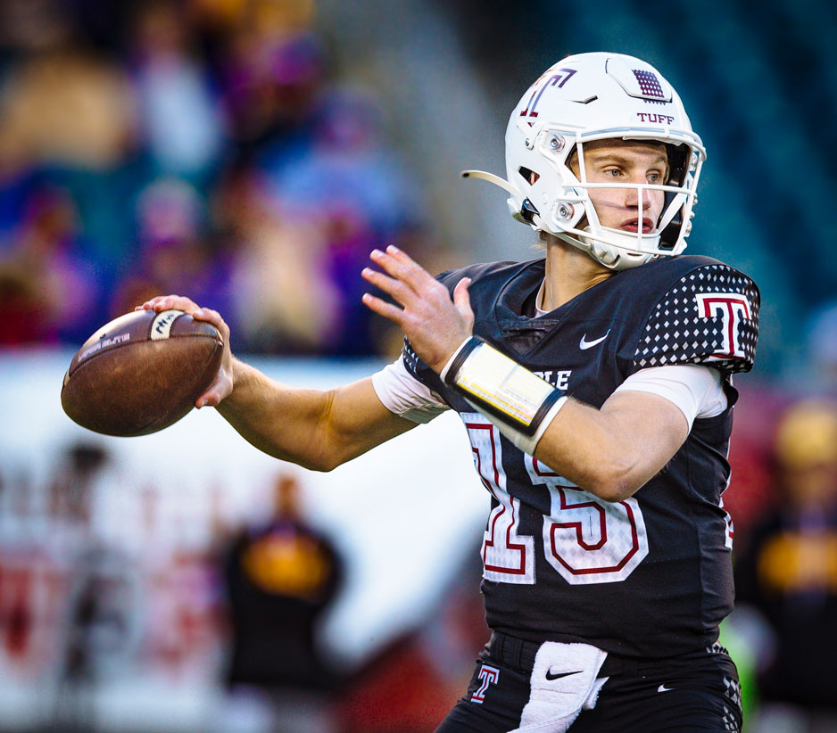 Image of a college athlete wearing a white helmet with a Temple logo and a black, cherry and white jersey, throwing a football.
