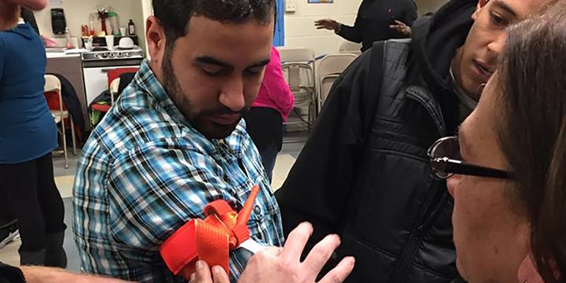 Community members learning to tie a tourniquet.