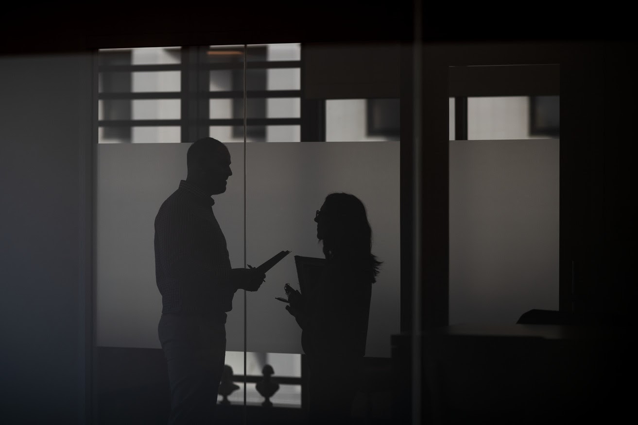 Two profiled silhouettes of two staff members talking with each other.