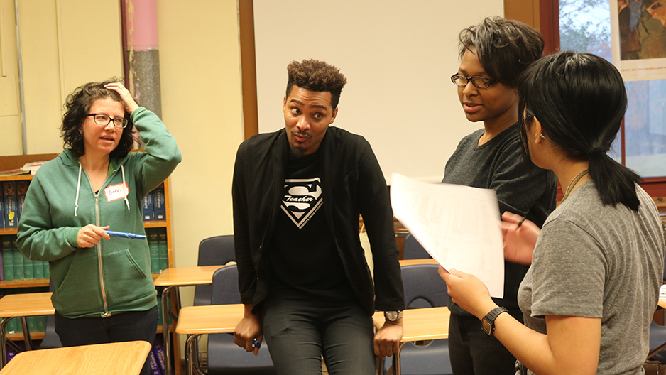 Four students and teachers working together in a classroom.