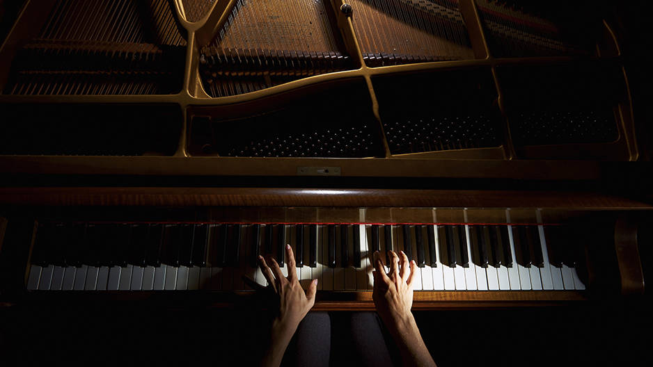 Hands playing a piano.