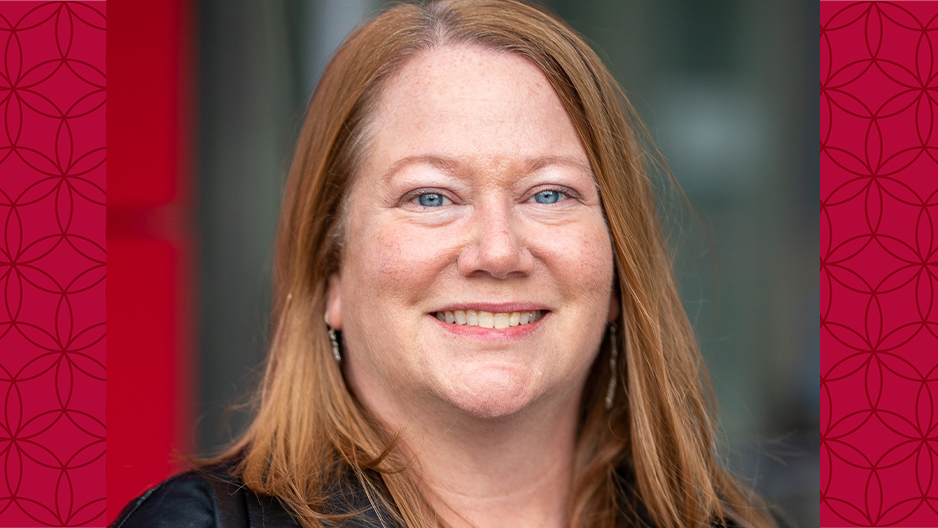 image of Jamie smiling at the camera against a red background wearing a black leather jacket