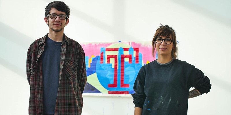 A man and woman standing in front of a painting.