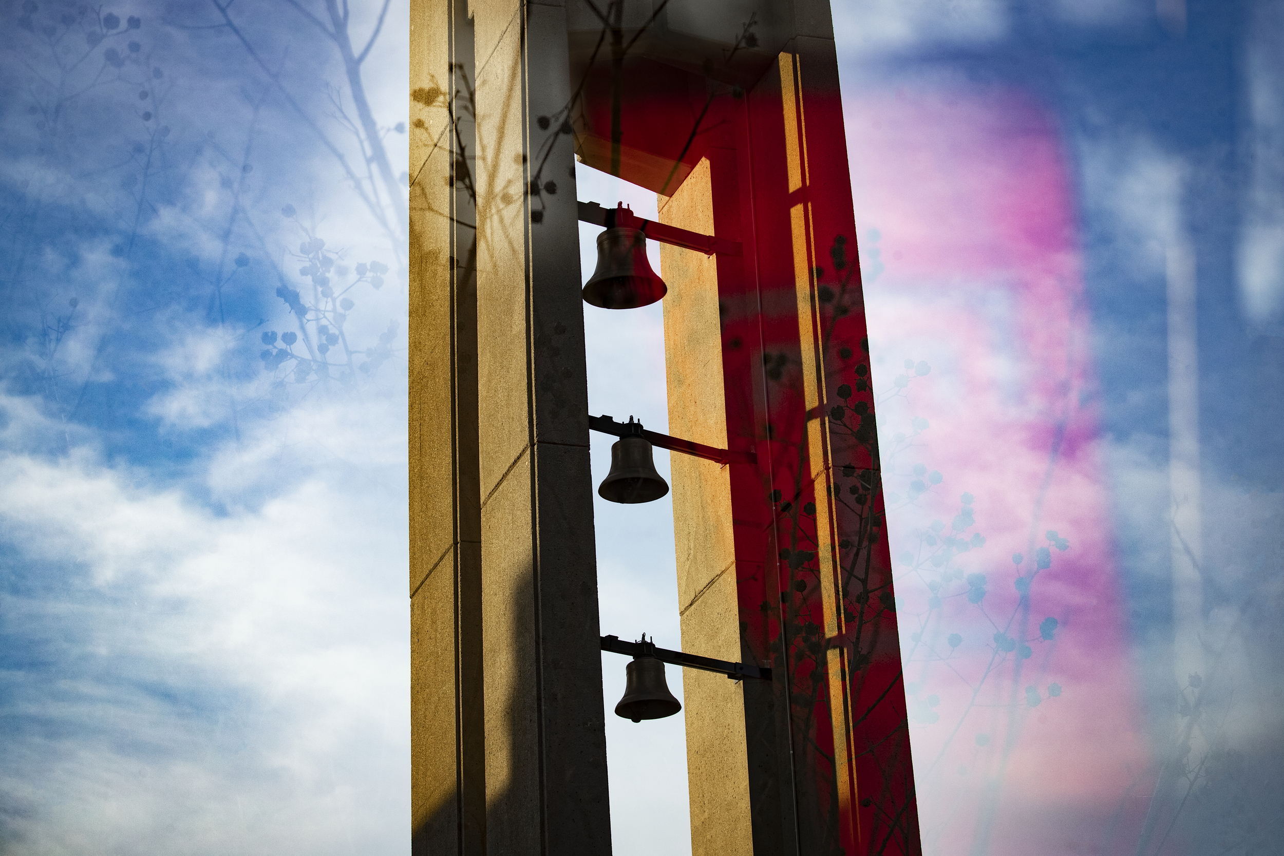 Slightly abstract photo of campus Bell Tower against blue skies with white whispy clouds