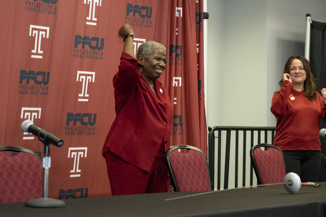 Image of Temple University’s former fencing coach Nikki Franke, wearing a cherry suit and pumping her fist.