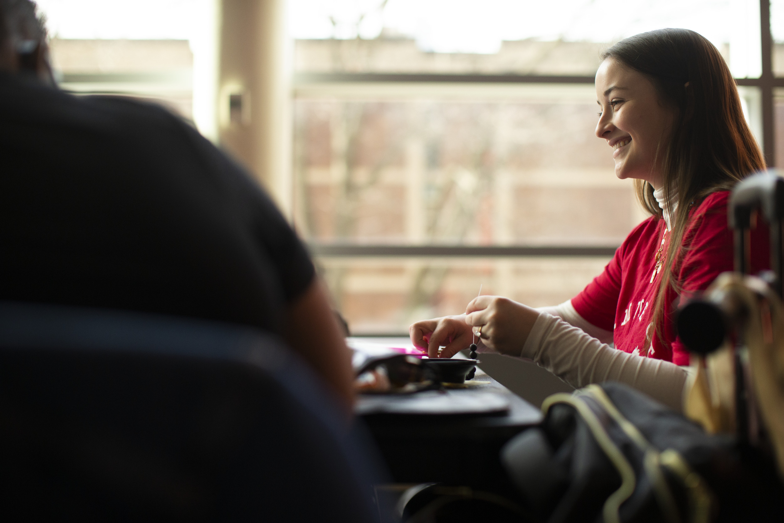 Person sitting at a table and smiling at another person not featured in the photo