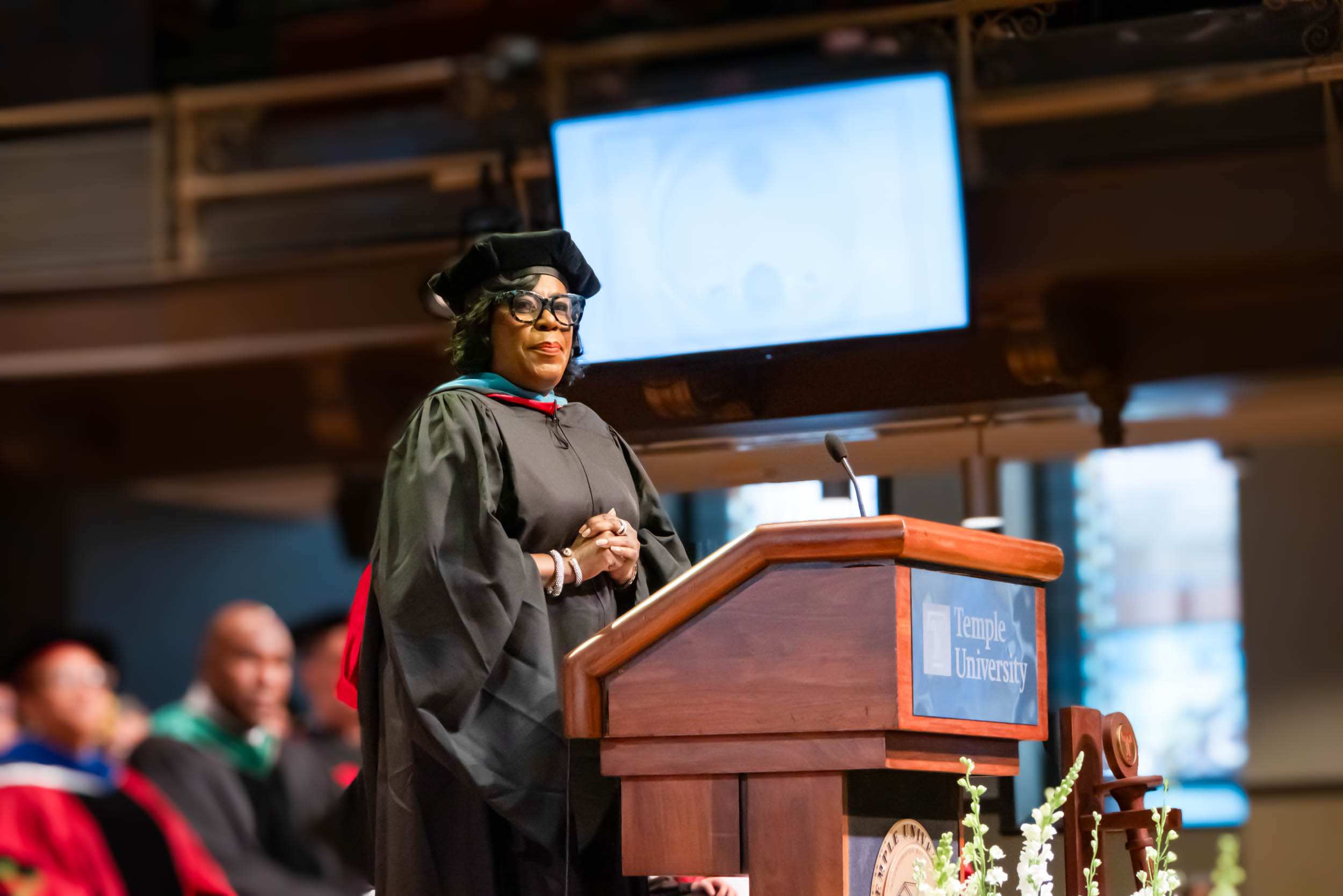 Mayor Cherelle L. Parker stands at a podium in academic regalia