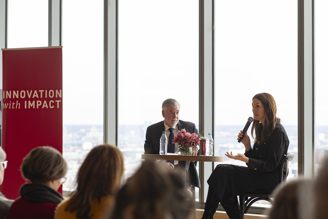 President John Fry and Professor Liz Moore speaking at a table in Morgan Hall in front of an audience