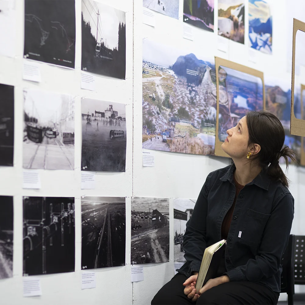 a seated student views architecture work displayed on a wall for review