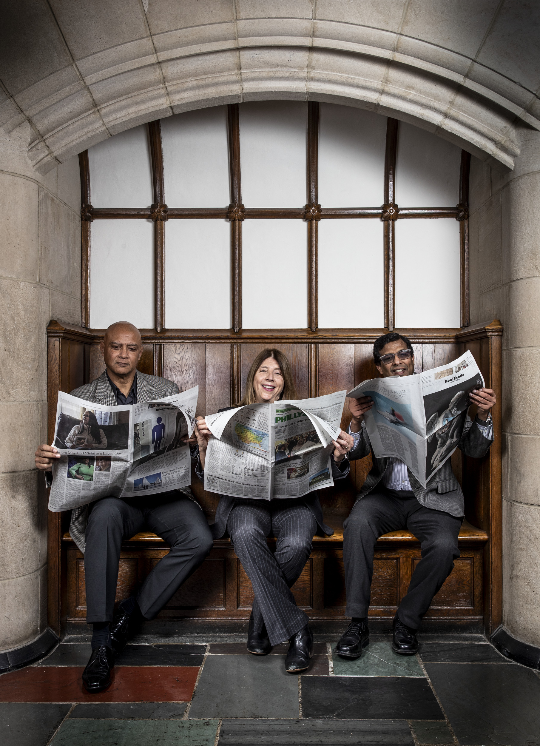 An image of the study's authors sitting on a bench reading newspapers.