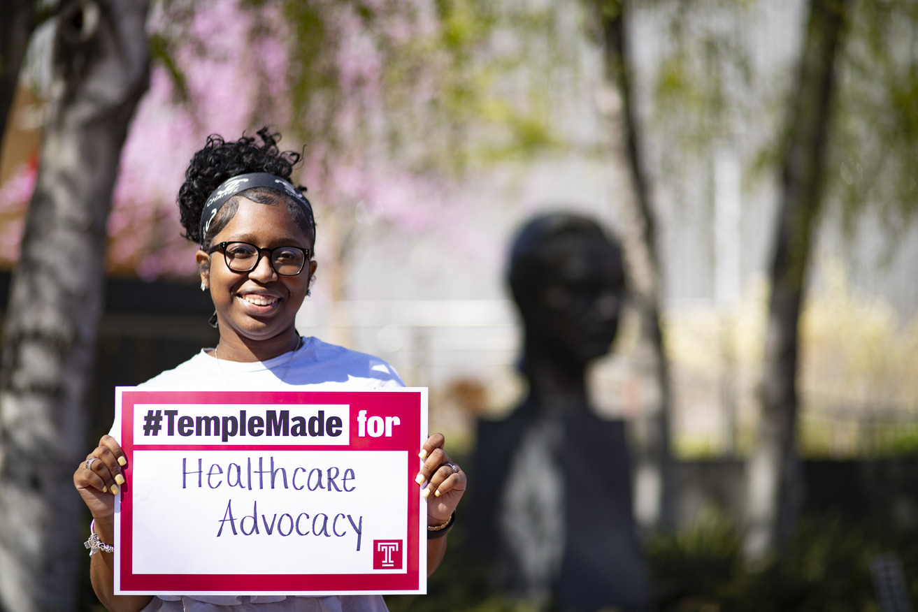 Image of India Byrd standing outside holding up a Temple Made for sign.
