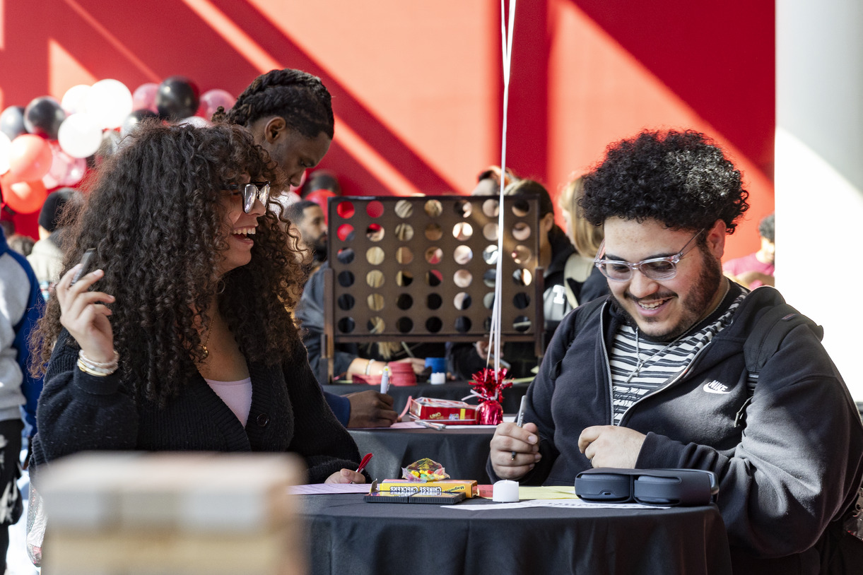 Two students laugh and play game at a table during the celebration
