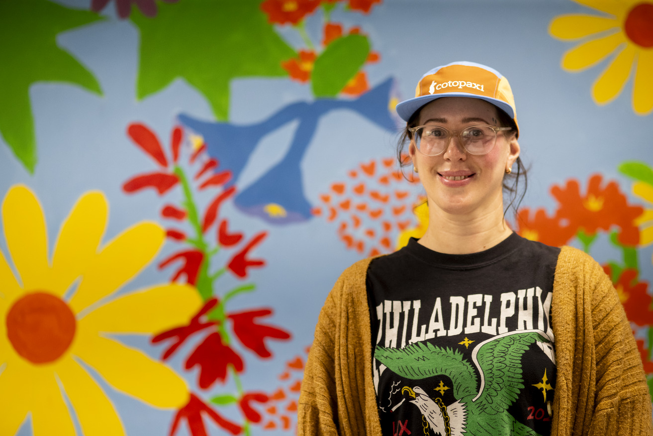 Temple student and Udall Scholar Lindsay Slusser is pictured in front of a floral mural on campus.