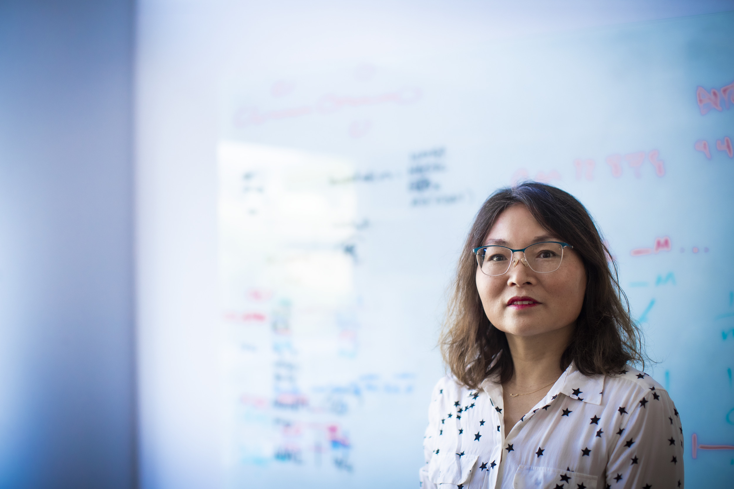 Xinghua Mindy Shi in front of a white board