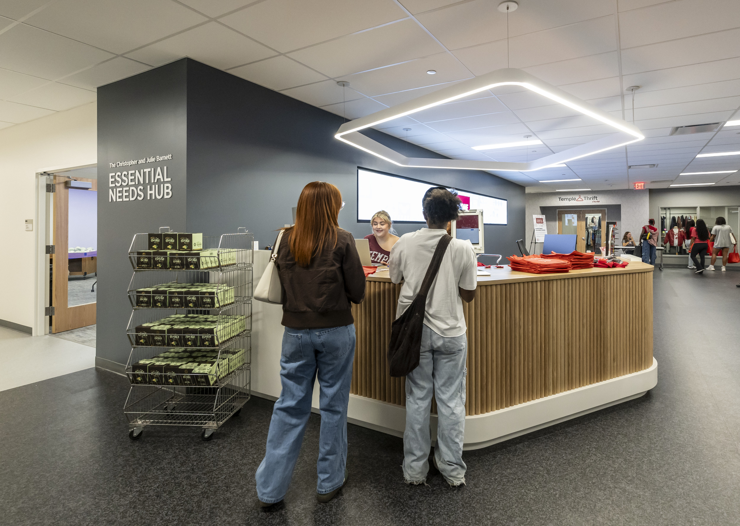 Students standing at a desk inside the Christopher and Julie Barnett Essential Needs Hub