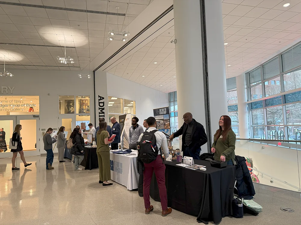 Students walking through the Tyler building lobby and looking at vendor tables at the 2025 AED Career Fair