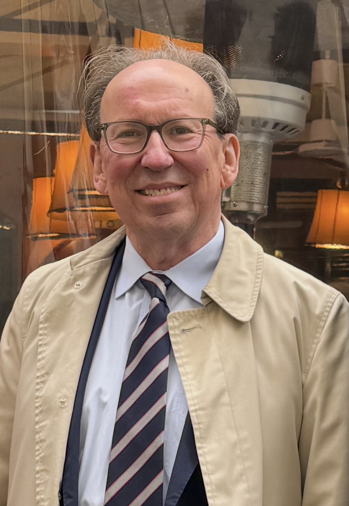 white male wearing glasses, short brow hair, stripe tie, tan jacket