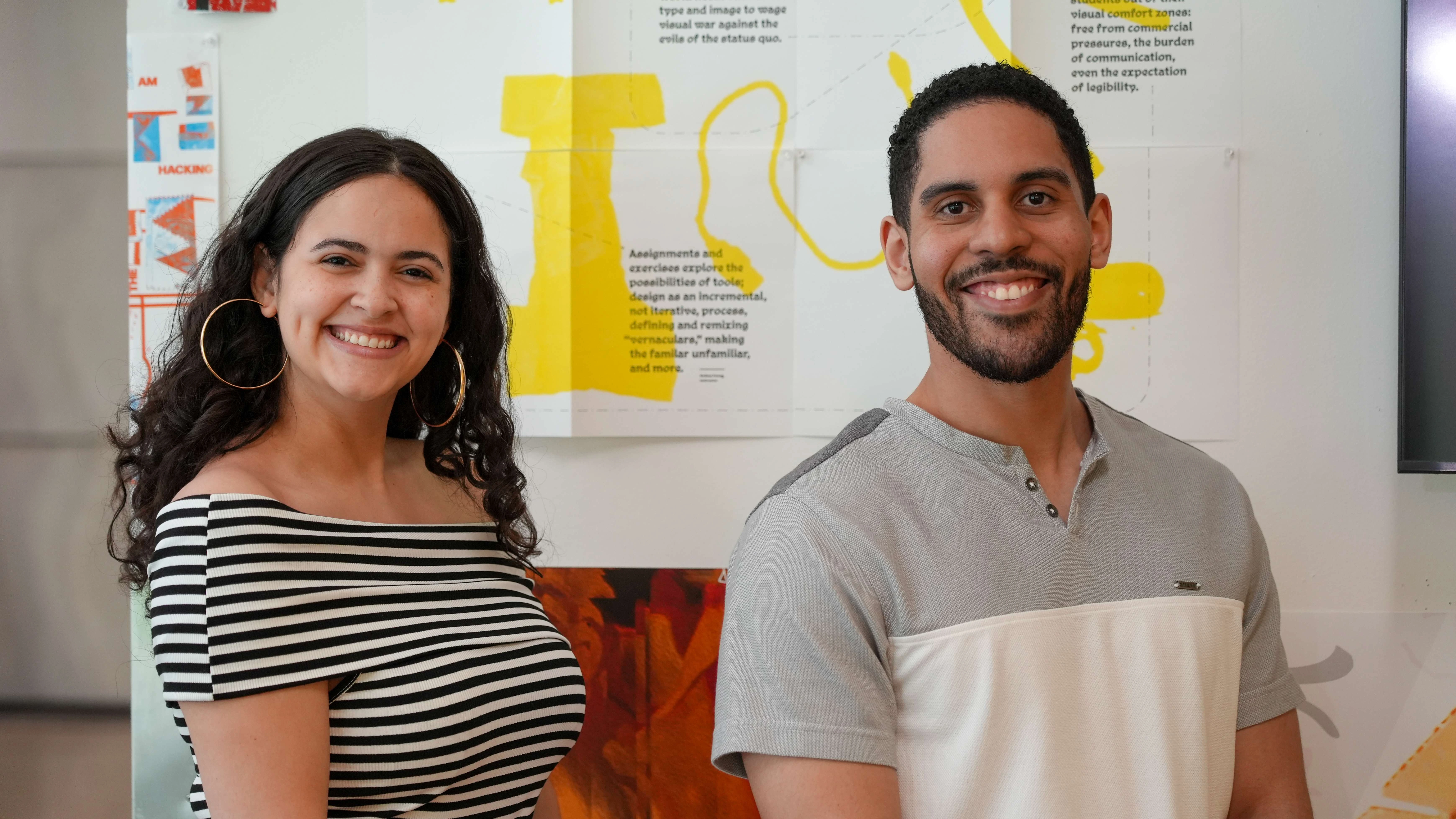 Emily Ramos and Said Nunez stand in front of design and illustration.