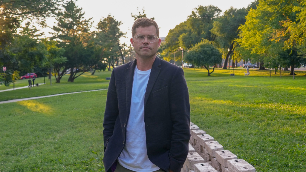 Jeff Richards stands in front of "flaxcrete" wall, part of the 2026 Art on the Parkway commission.
