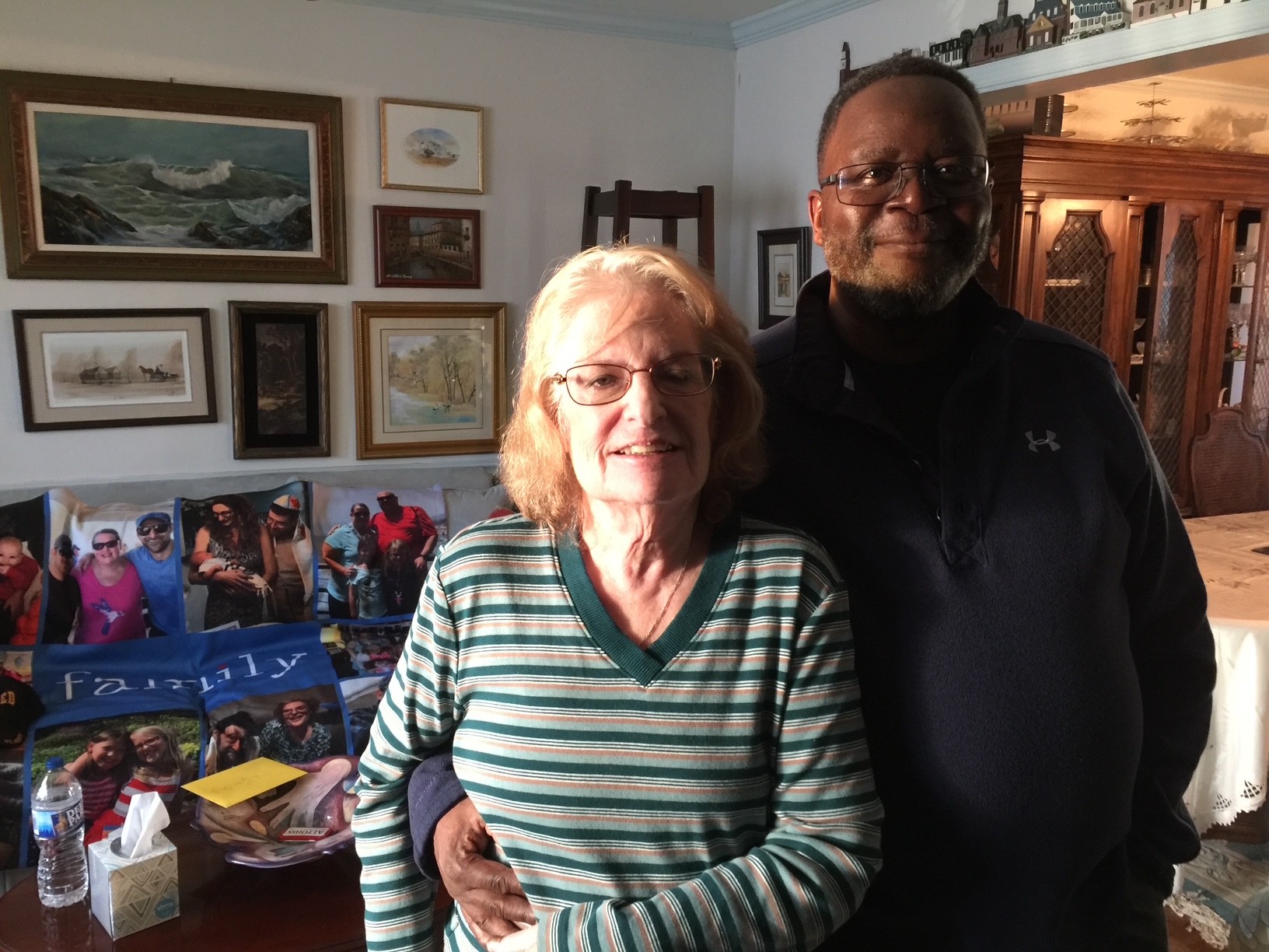A middle-aged man stands with his arm around an older woman
