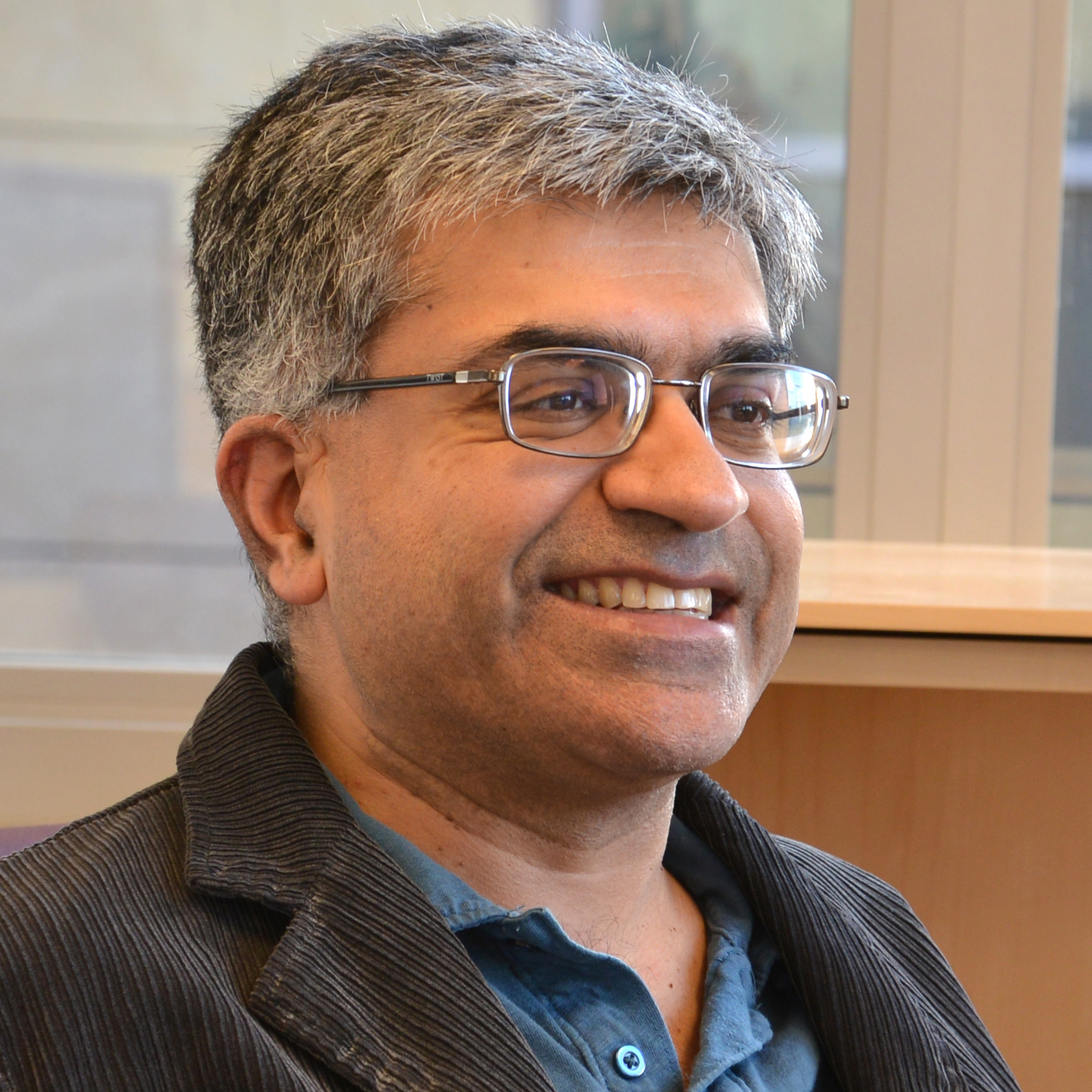 A photo of Harsh Deep Chopra looking to the side and smiling.