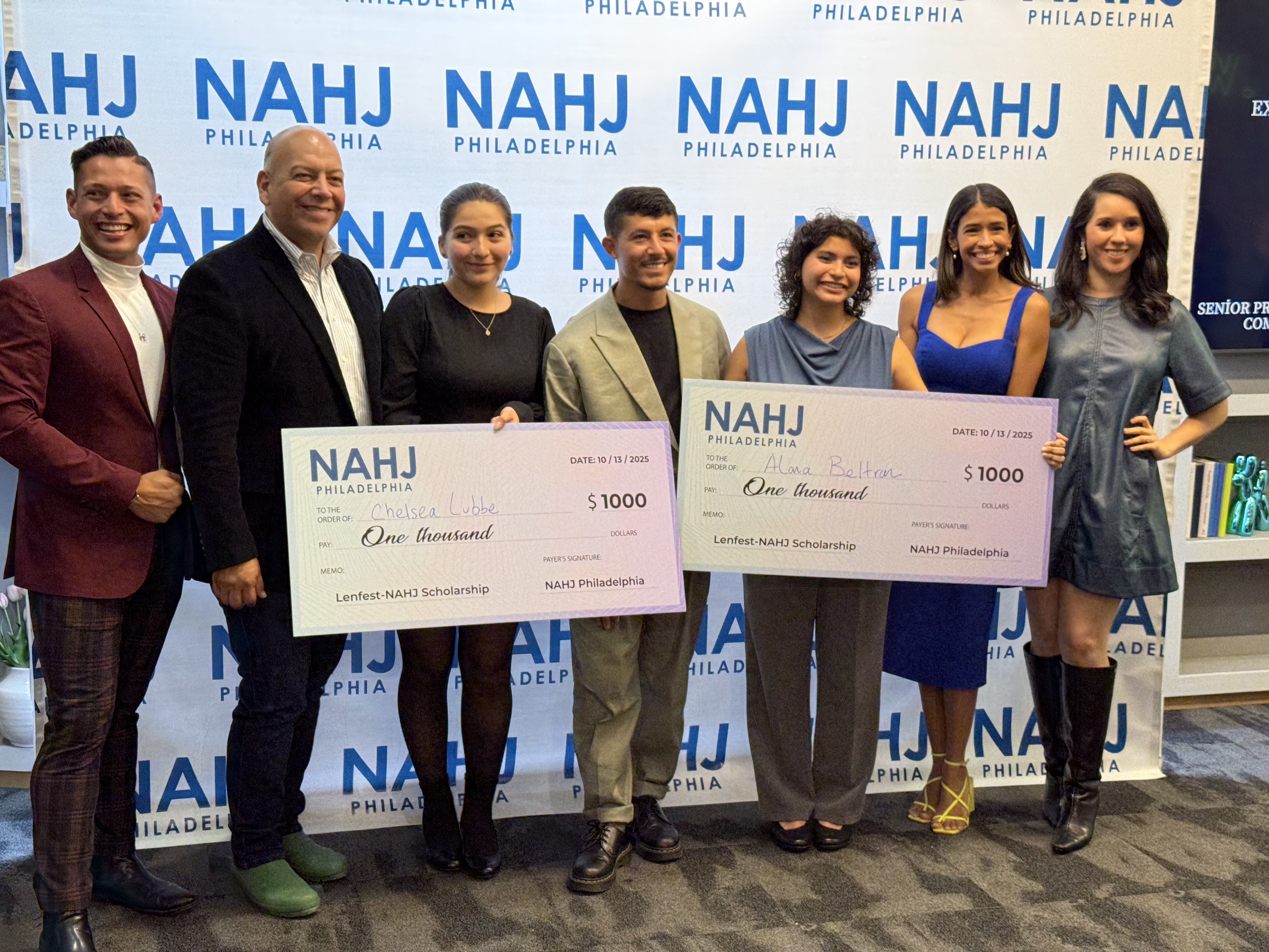 People smiling in front of an NAHJ banner