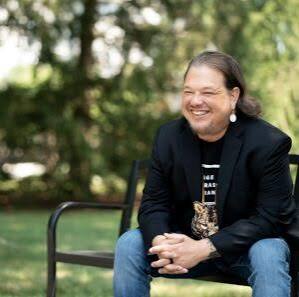 image of Jeremy sitting on a bench smiling into the distance