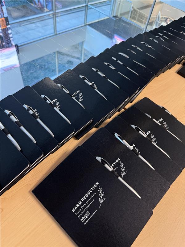 Black journals promoting harm reduction lined up on table.