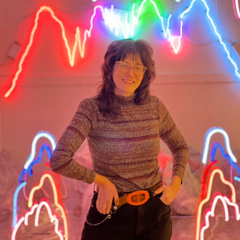 decorative thumbnail of Alissa Eberle standing in front of her neon installation.