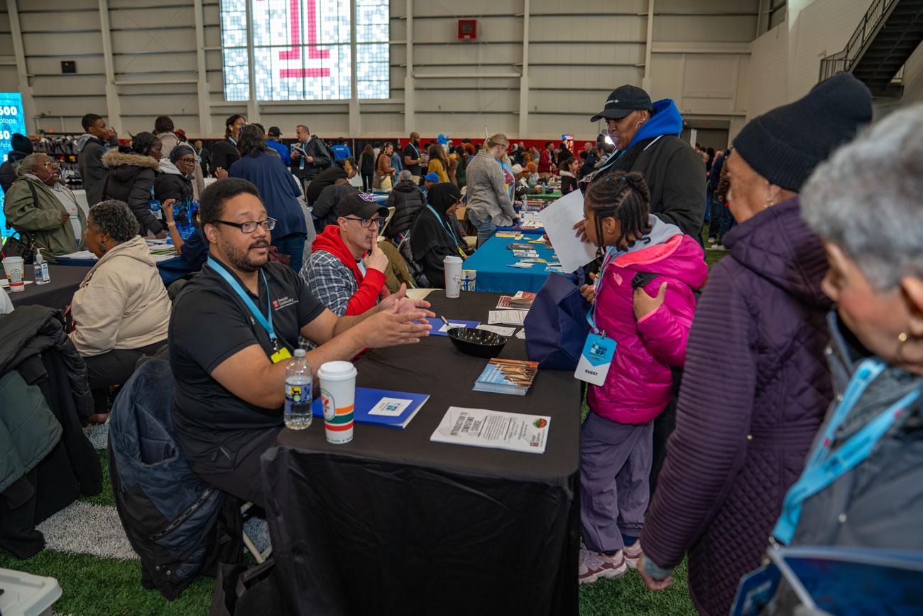 Image of Philadelphia residents holding laptops on stage at Temple.