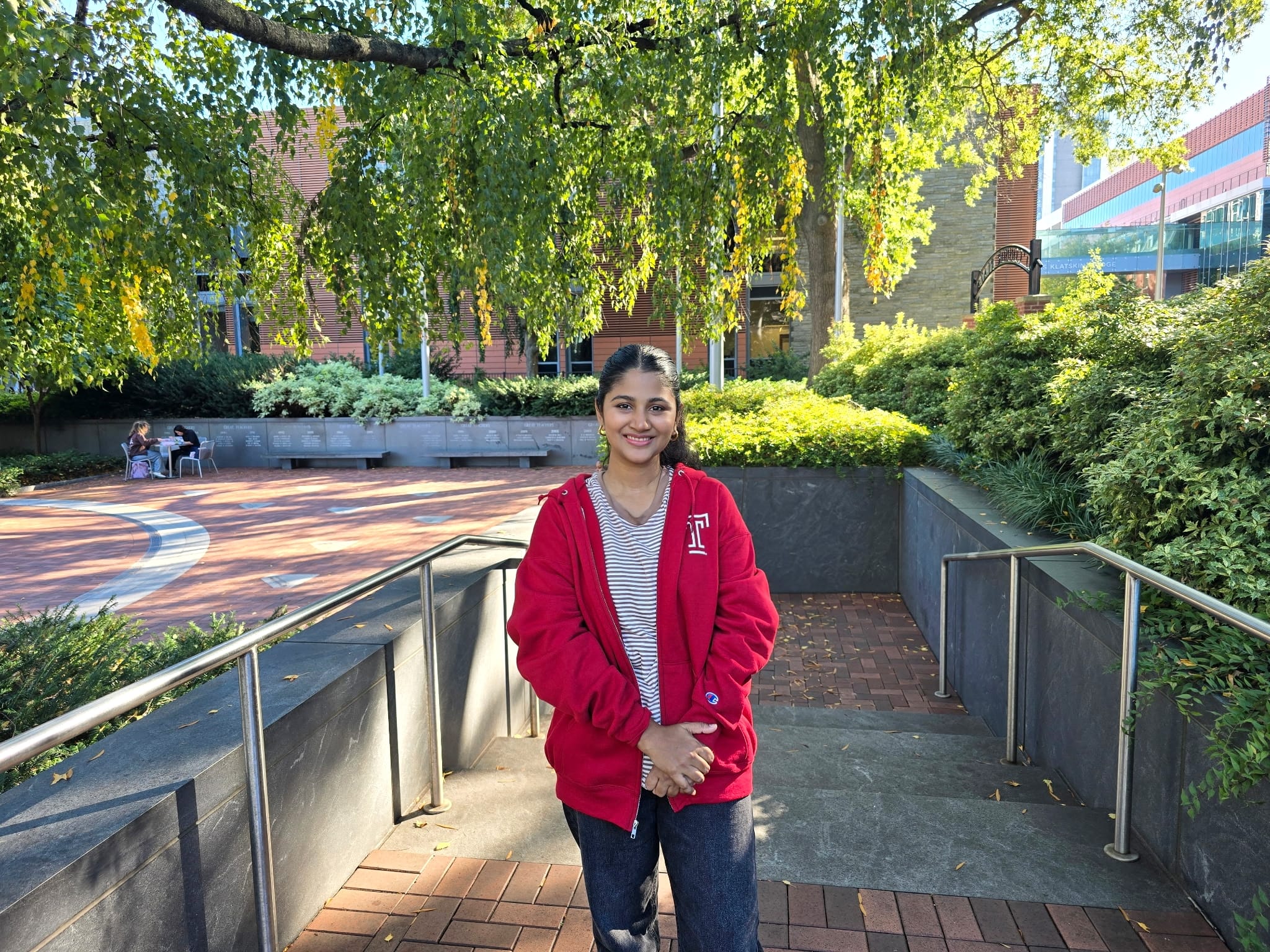 A woman stands with her arms folded in front of her at the brick ramp entrance to Temple University's Founders Garden