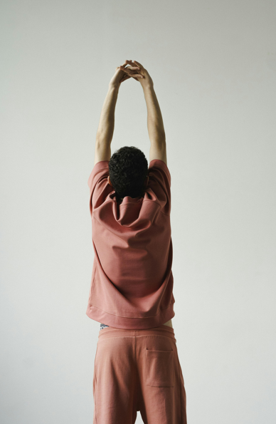 Person standing with back to camera and stretching arms up into the sky 