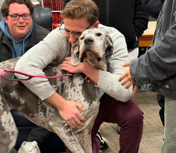 A happy health sciences student hugging one of the therapy dogs, who looks pretty happy too.