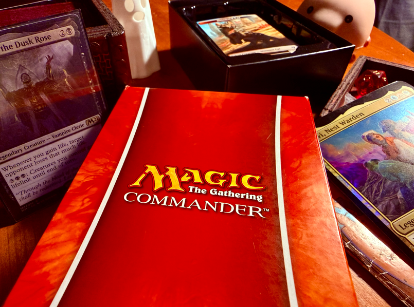 The game box for Magic: The Gathering Commander, surrounded by cards from the game. 