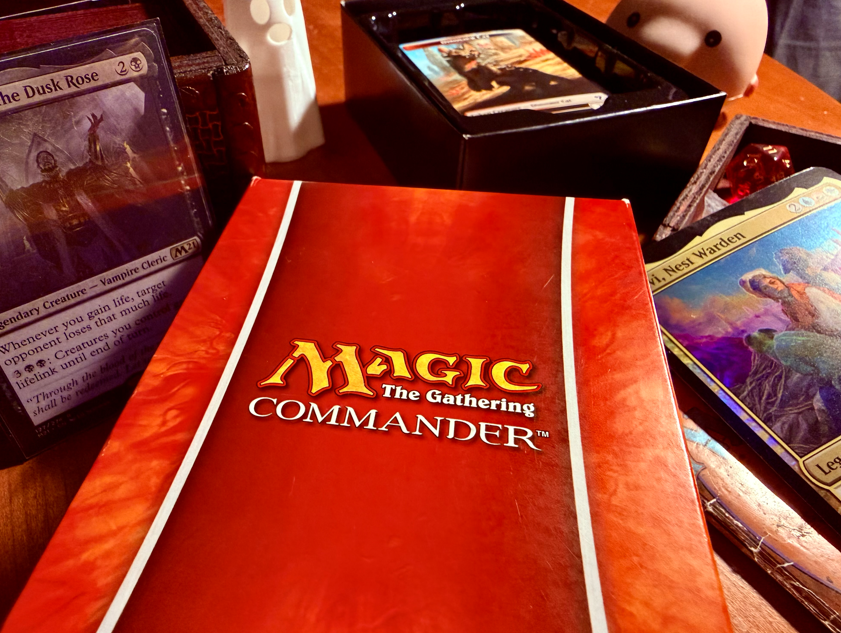 A book cover with “Magic: The Gathering Commander” on the front, surrounded by Magic: The Gathering cards. 