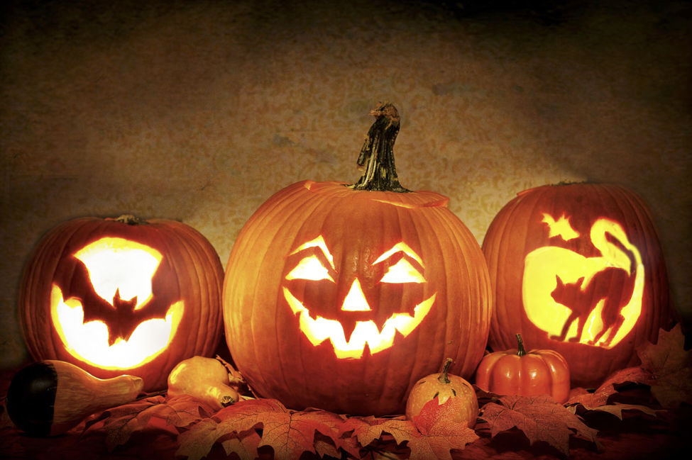 Glowing jack-o'-lanterns surrounded by autumn leaves.