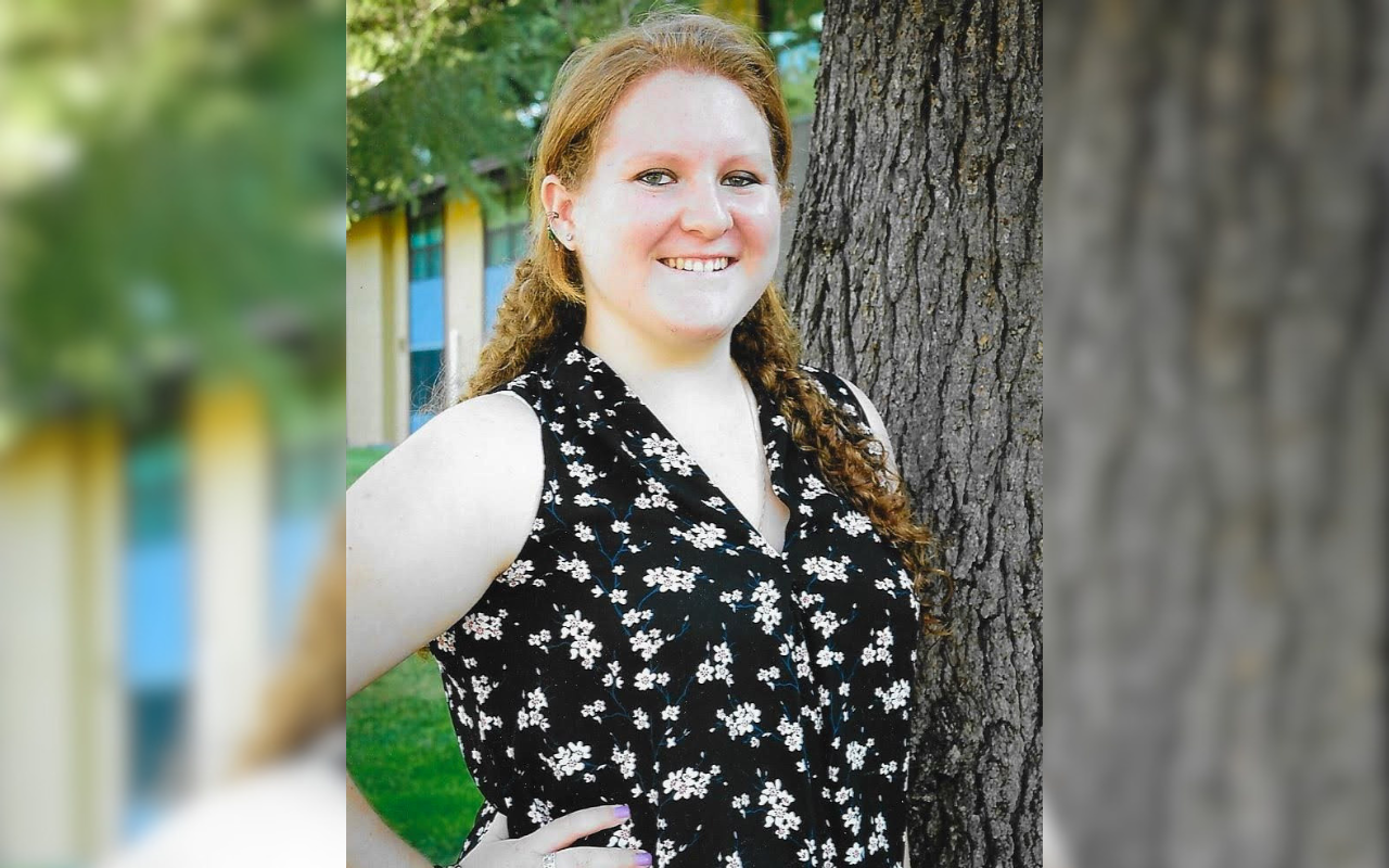 A women with red hair standing by a tree