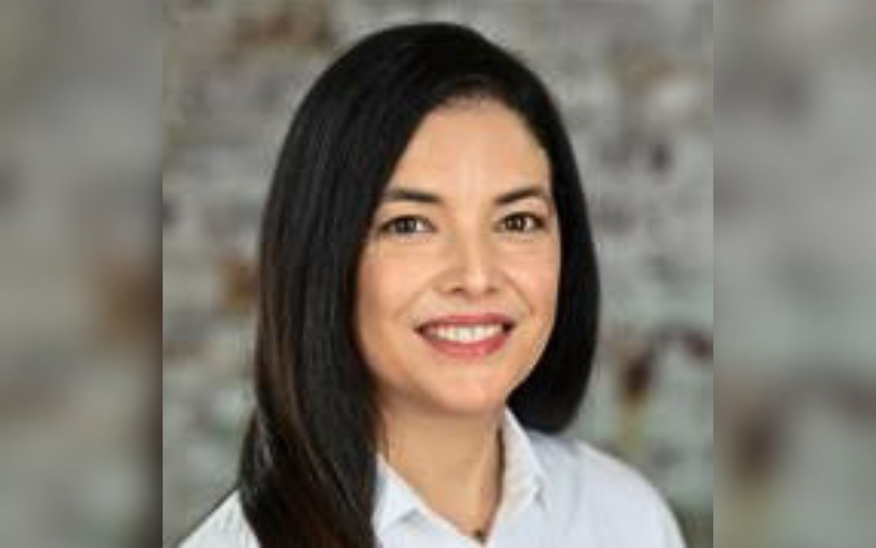Woman with dark hair and white shirt smiling