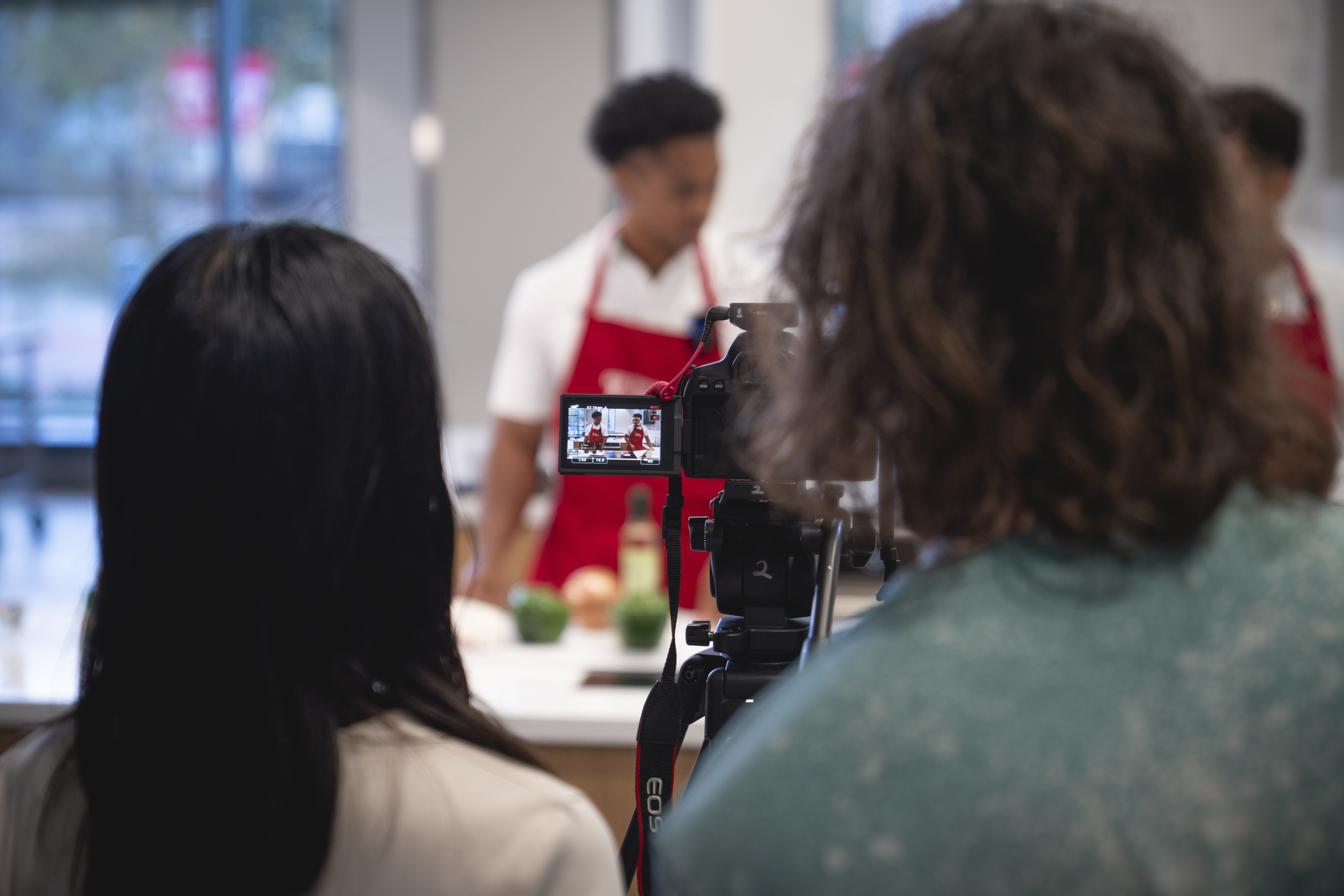 Camera filming people cooking in aprons