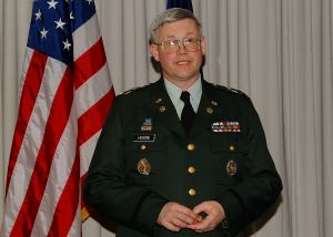 image of Jonathan House standing in his military uniform with American flags in the background