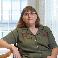 image of Elizabeth in a green shirt wearing glasses smiling at the camera