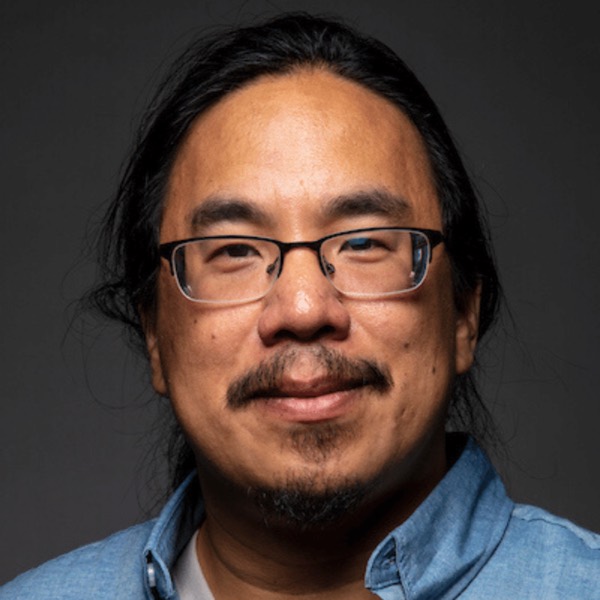 Thi Nguyen wearing glasses and mustache with close cropped hair