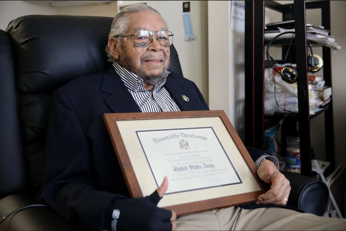 Nelson Henry Jr. holding his honorable discharge certificate.