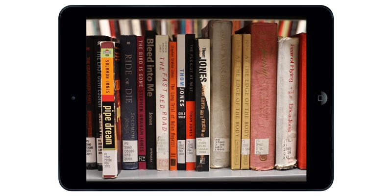 An iPad with a photo of book spines on the screen.