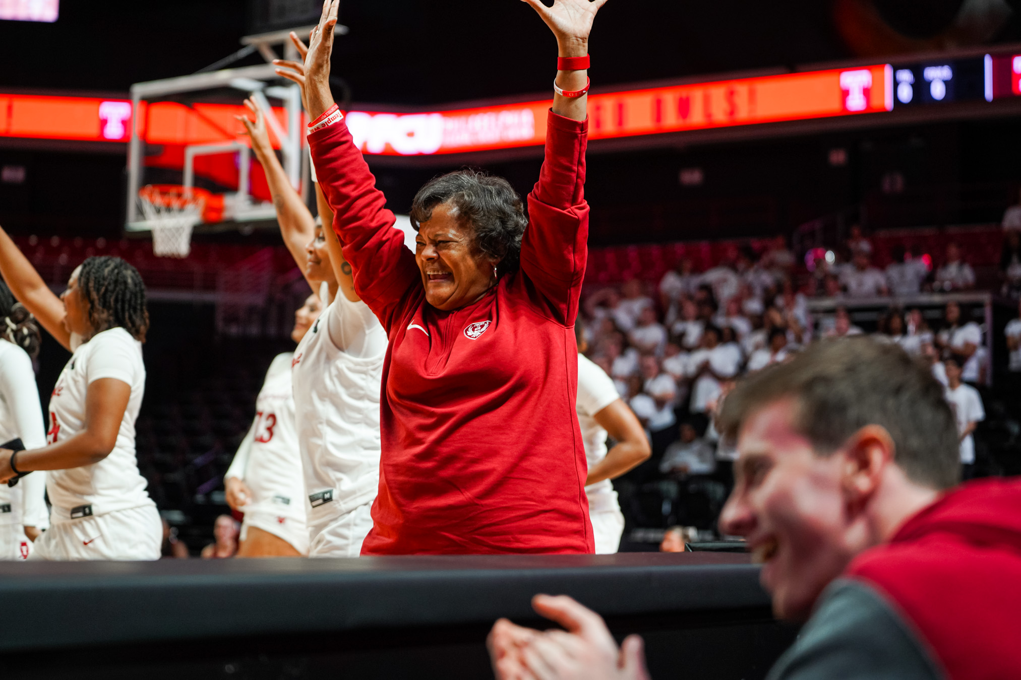 Image of Temple University s Coach Diane Richardson smiling and raising her hands during a college basketball game.